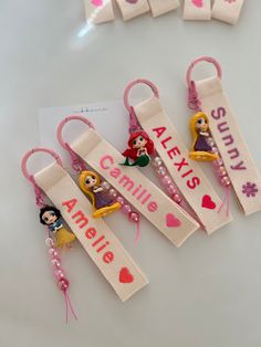 four personalized keychains with princesses on them and name tags attached to them