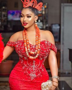 a woman in a red dress with beads on her head and necklaces around her neck