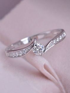 a diamond ring on top of a pink velvet covered surface with white diamonds in the band