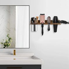 a bathroom with a sink, mirror and hairdryers on the wall above it