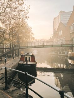 a small boat floating on top of a river next to a bridge in the middle of town