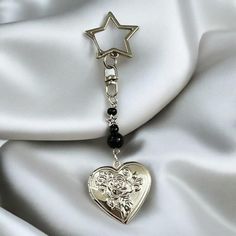 a heart shaped keychain with a star hanging from it's side on a white satin background