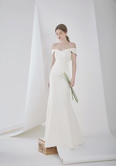 a woman in a white wedding dress holding flowers