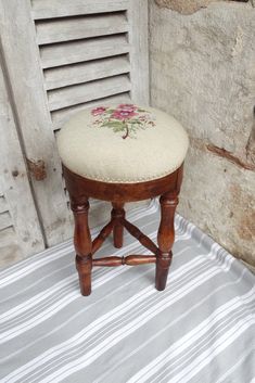 a wooden stool with a flower embroidered seat