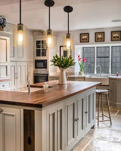 a large kitchen with an island in the middle and two pendant lights hanging from the ceiling