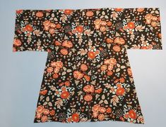 an orange and black flowered kimono is laying on a blue surface with white background