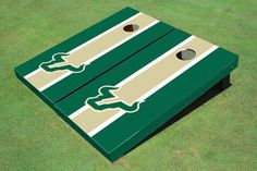 a pair of green and white striped cornhole game boards on grass with holes in the middle