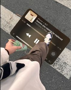 a person standing on the street with their feet up in front of an electronic device