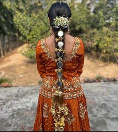 a woman in an orange dress with flowers on her head and necklaces attached to her neck