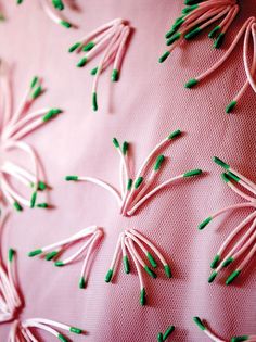 pink fabric with green pins and thread on the back of it's surface, close up