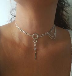 "♦ A chain choker made of sterling silver with O ring and spike pendant. the coker necklace is dainty And styled inspired by the punk style. Suitable for both evening and daytime performances SIZE Length: 11.8\" (30cm) up to 15.8\"(40cm) width chain:0.16\" (0.4\" cm) wide hoop: 0.59\" (1.5cm) high spike : 0.59\" (1.5cm) You can see earrings set in the next link: https: https://etsy.me/2U49YlD ♦ This piece of jewelry is perfect as a gift for yourself, friend for the wedding day, Valentine's day o Spike Choker, Alternative Earrings, O Ring Choker, Lariat Necklace Silver, Day Collar, Charm Choker Necklace, Edgy Jewelry, Evening Jewelry, Silver Link Chain