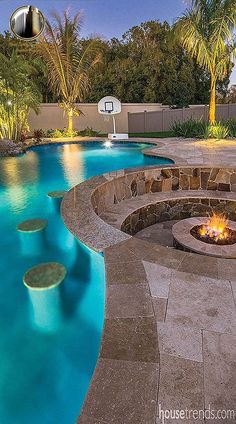 an outdoor swimming pool with fire pit and basketball hoop in the middle, surrounded by palm trees