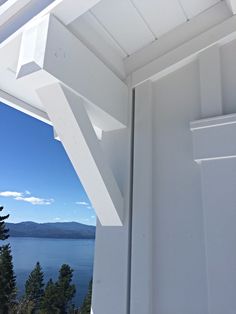 an open window on the side of a building with water and trees in the background