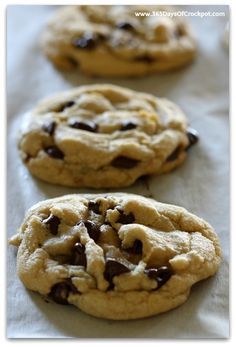 three chocolate chip cookies sitting on top of a table