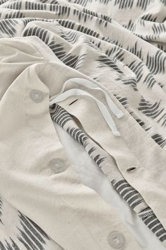 an unmade bed with black and white patterns on it