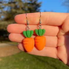 two carrots with green tops are hanging from earrings