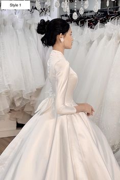 a woman in a white dress standing next to wedding dresses