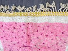 a pink and white rug on top of a wooden floor next to a black wall