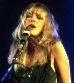 a woman singing into a microphone on stage