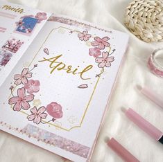 an open notebook with pink flowers and the word april written in gold foil on it