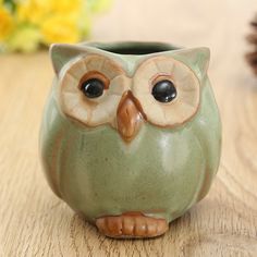 a ceramic owl cup sitting on top of a wooden table