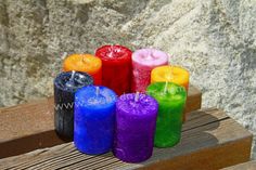 seven colored candles sitting on top of a wooden bench