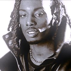 a black and white photo of a man with dreadlocks