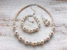 a necklace and bracelet with pearls on a wooden surface, set against a white background