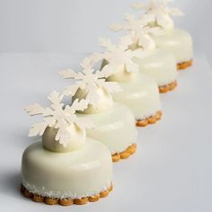 four desserts with white frosting and snowflakes on them are lined up