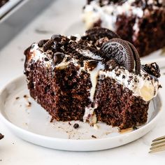 a slice of chocolate cake with oreo cookies and cream frosting on a white plate