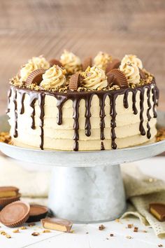 a cake with chocolate and peanut butter frosting on a silver platter next to cookies