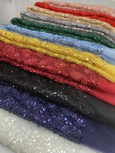 many colors of sequin fabric are stacked on top of each other in this image