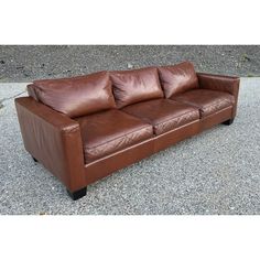 a brown leather couch sitting on top of gravel