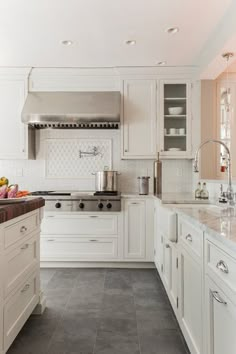 a kitchen with white cabinets and marble counter tops