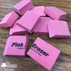 pink erasers on a wooden table with the word eraser written in black ink