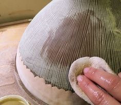 a person is working on a vase that has been made with clay and then sand