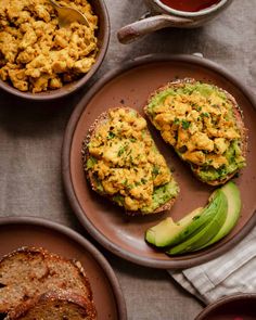 two plates with eggs and avocado on them next to some other food items