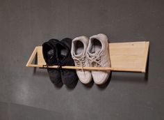 three pairs of shoes are hanging on a wall with a shoe rack attached to it