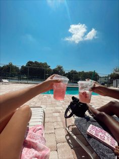 two people are sitting on the beach with drinks