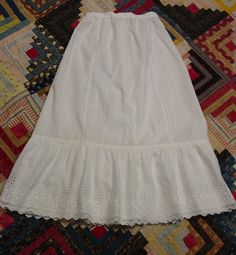 This is a charming antique Edwardian petticoat in excellent condition. It is white cotton and measures 28" in length. The waist is 22" and there is a 10" placket in the back with a snap and a pearl button at the waist. It is tightly shirred in the back and is and is nice and full. It has a lovely embroidered ruffle with a scalloped edge and there is a 1" pleat that I believe was to lengthen when needed. It is in excellent condition- clean (just washed and pressed) and has no spots or holes. I combine shipping and am happy to provide a shipping quote to international shoppers. Thanks for visiting... White Regency Style Petticoat With Ruffles, Regency Style Ruffled Petticoat For Daywear, Vintage Petticoat For Summer Daywear, Daywear Ruffled Petticoat, White Cotton Petticoat With Attached Cancan, Victorian White Ruffled Petticoat, Victorian White Petticoat With Ruffles, Vintage Petticoat With Attached Cancan For Spring, White Regency Style Cotton Petticoat