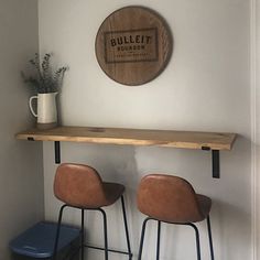 two bar stools sitting on top of a wooden shelf in front of a wall