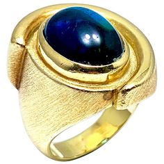 A gorgeous Indicolite Tourmaline fashion ring designed by Bruno Guidi. The 6.43 cabochon Indicolite displays a lustrous teal color, bezel set in an 18 karat yellow gold abstarct design ring. The inside shank is signed "Bruno Guidi" and stamped "18K Brazil". This is currently a size 6.25, and can be adjusted. Offered by Charles Schwartz & Son Jewelers. Indicolite Tourmaline, Fashion Ring, Teal Color, Teal Colors, Yellow Gold Rings, Bezel Setting, Estate Jewelry, Ring Designs, Gold Ring