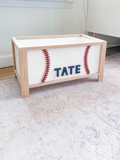 a baseball themed toy box with the word tate on it, sitting on a rug