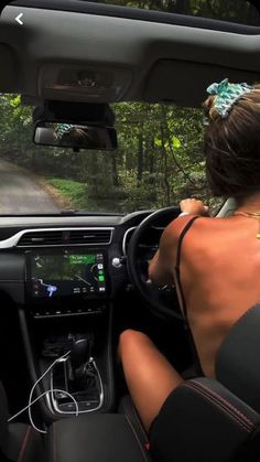 a woman driving a car down a forest road