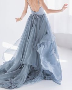 a woman in a long blue dress with her arms out and one hand on her hip