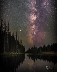 the night sky is filled with stars and milky over a lake in the woods,