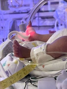 a baby laying in a hospital bed next to a tube