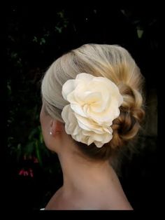 a woman with blonde hair wearing a flower in it's buns and has her back to the camera