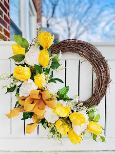 a wreath with yellow and white flowers on a fence