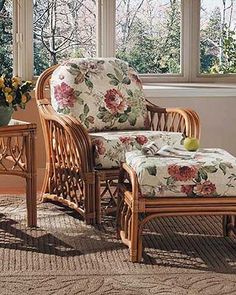 a wicker chair and foot stool in front of a window with flowers on it